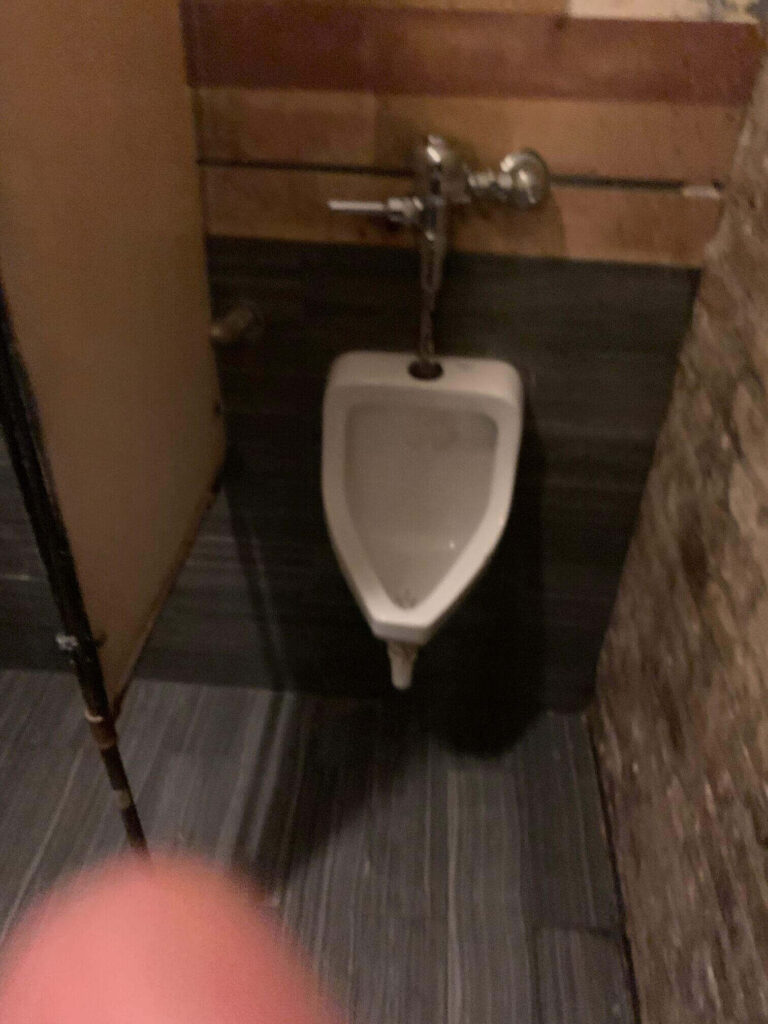 Urinal with a thumb at the bottom of the shot