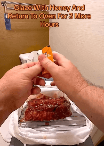 A piece of ribs with two hands applying honey to it